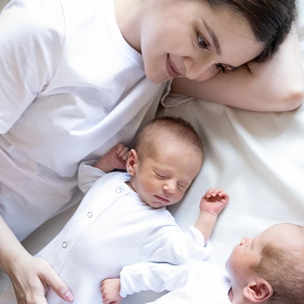 A mother smiling at her two newborn babies