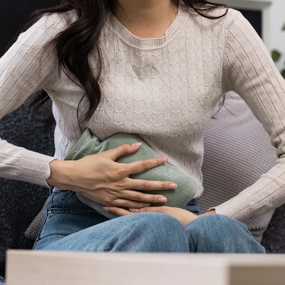 Woman holding a heating pad to her abdomen